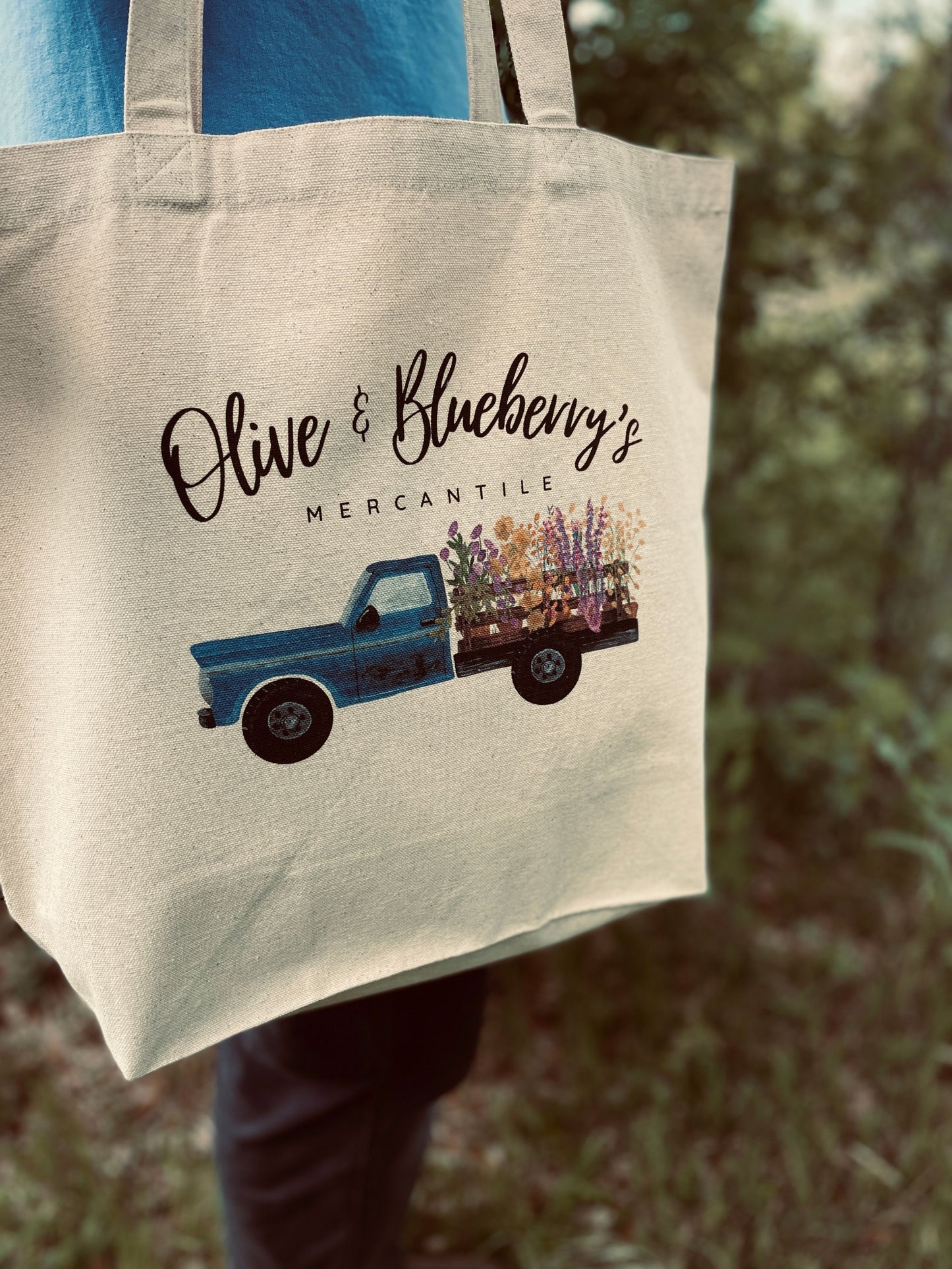 Back view of cotton canvas tote bag with blue farm truck logo and flowers