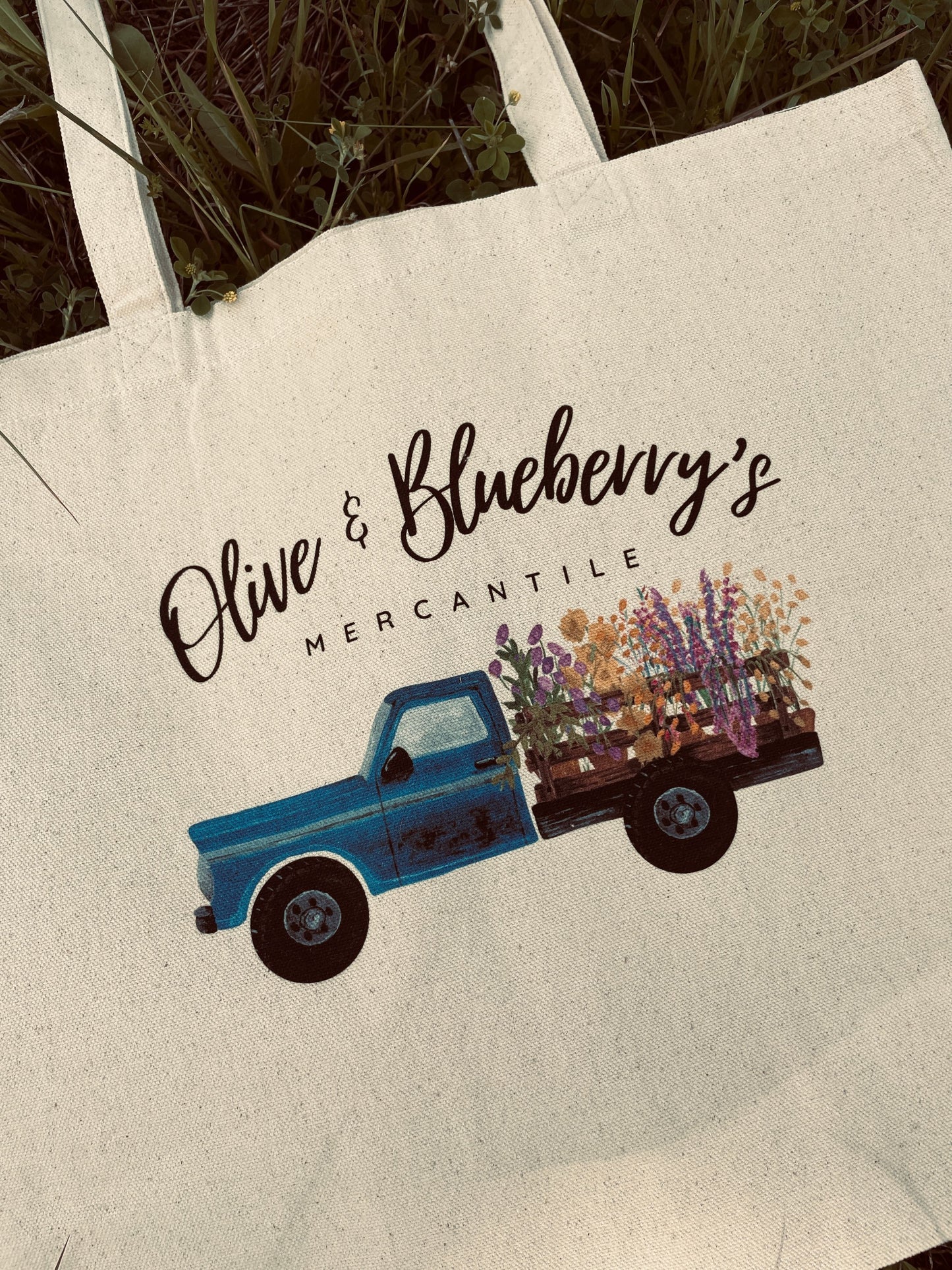 Close-up detail of blue farm truck logo with flowers on cotton canvas tote bag