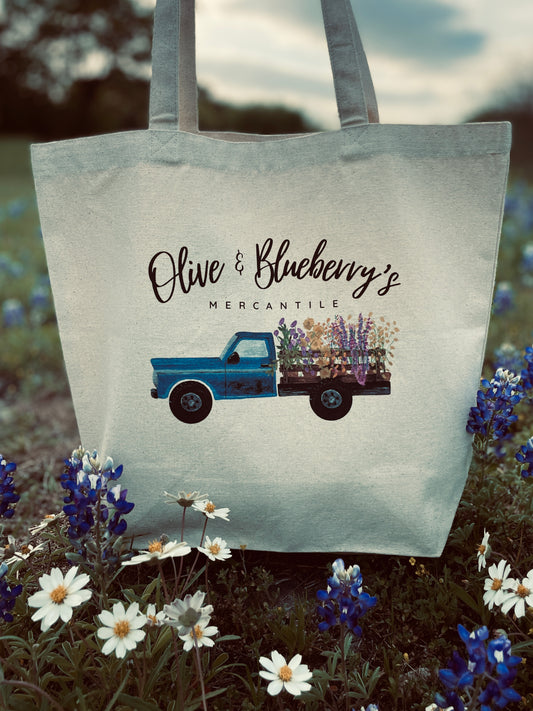 Back view of cotton canvas tote bag with blue farm truck and floral logo