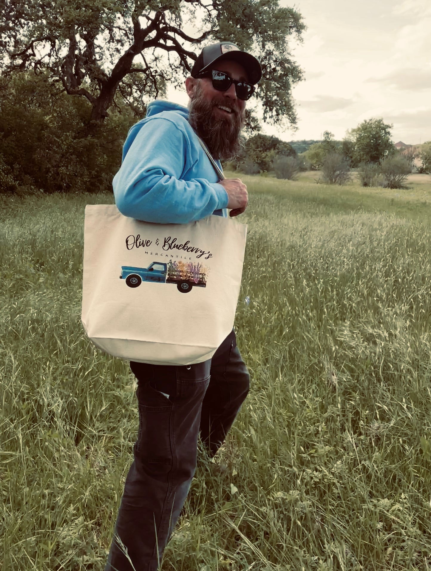 Cotton canvas tote bag with blue farm truck logo being used at a farmer's market