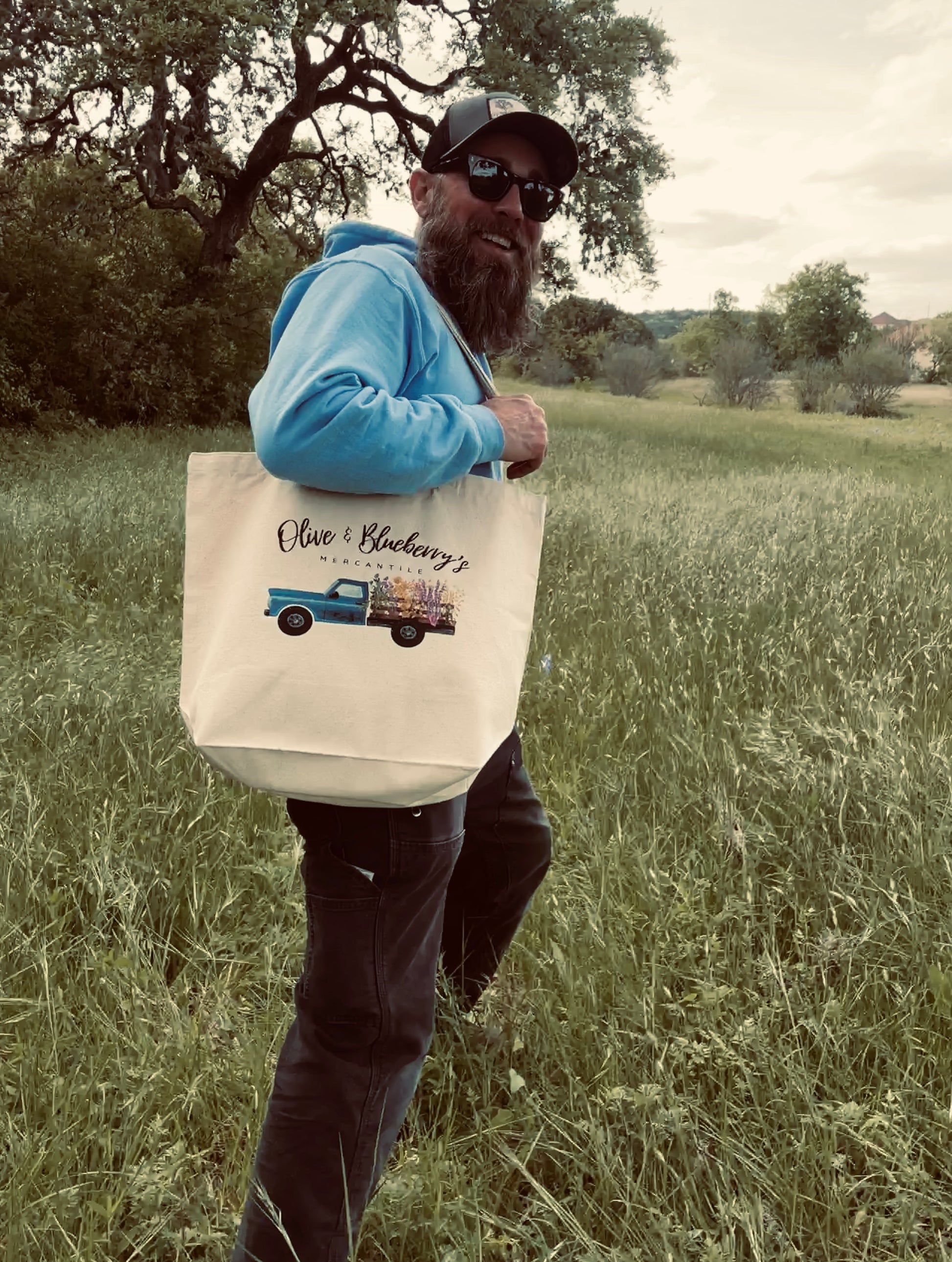 Cotton canvas tote bag with blue farm truck logo being used at a farmer's market
