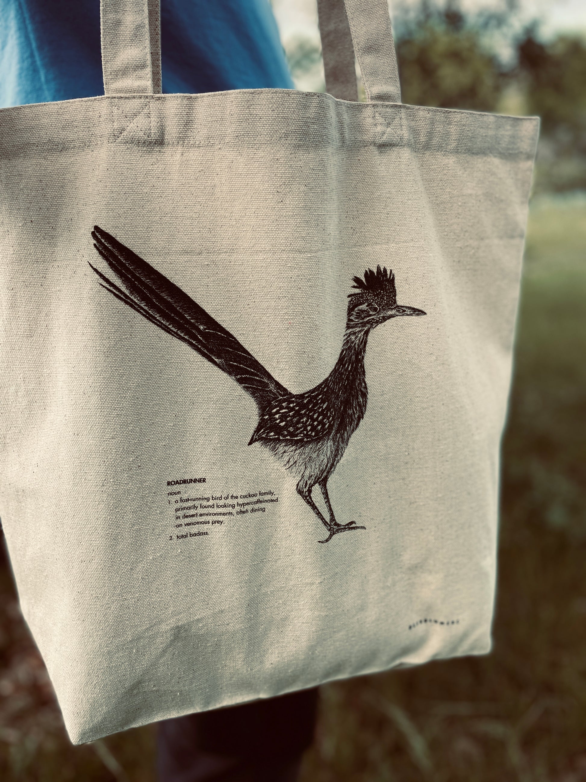 Front view of 100 percent cotton canvas tote bag featuring a realistic roadrunner illustration with a funny definition